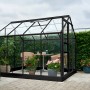 Schwarzes Halls Gewächshaus Popular 86 (5 m²) mit Pflanzen und Sitzgruppe im Garten.