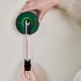 Bosch Atino Linienlaser selbsthaftend an Wand mit Laserlinie und Maßband zur Ausrichtung.