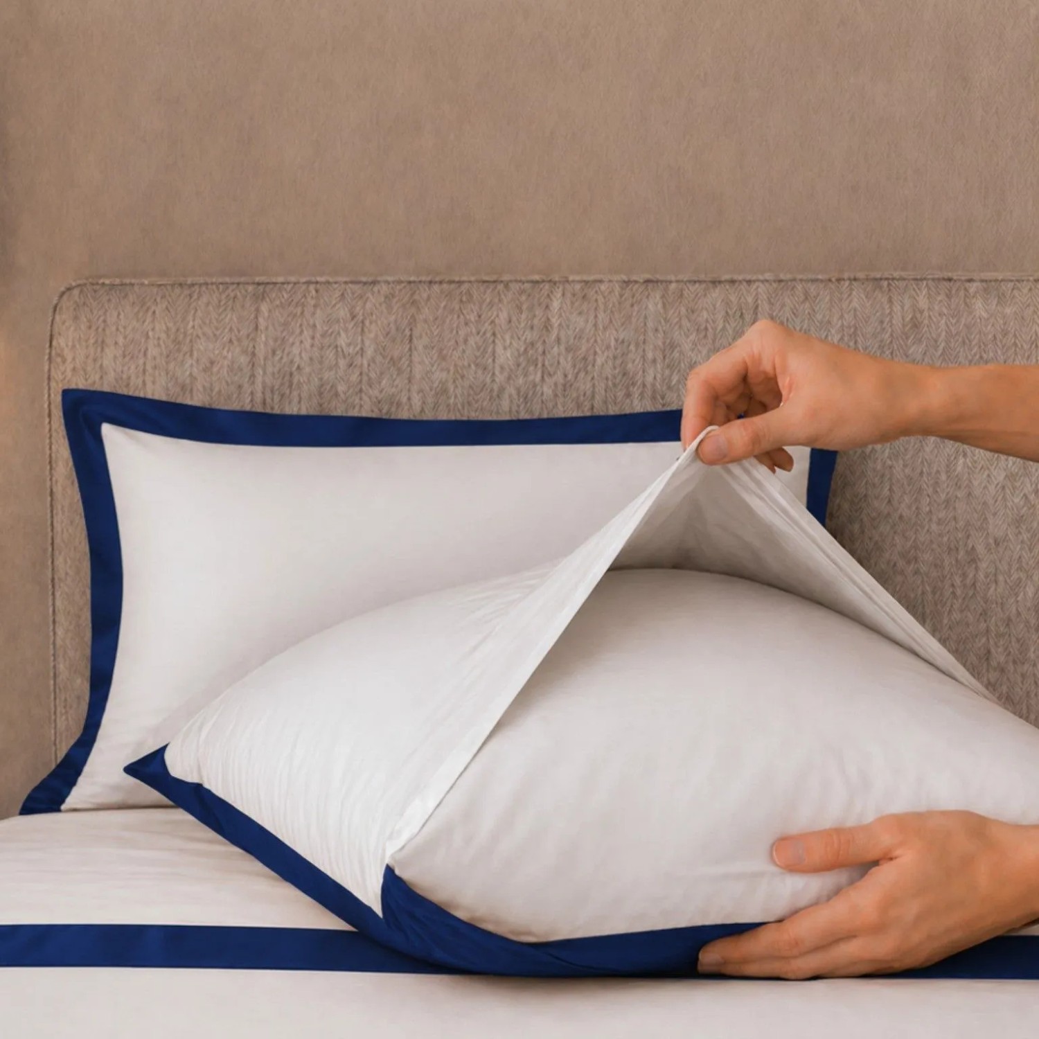 Weißer Baumwoll-Kissenbezug mit blauer Satin-Bordüre, eine Hand zeigt die Innenseite. The White Stone Einzelbett Bettwäsche.