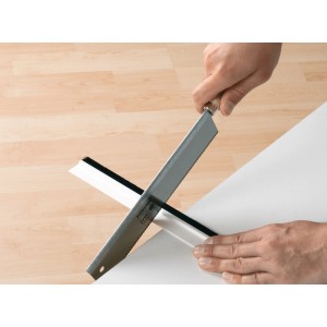 Zuschnitt der weißen Tesamoll Comfort Türdichtschiene für unebene Böden mit einer Säge.