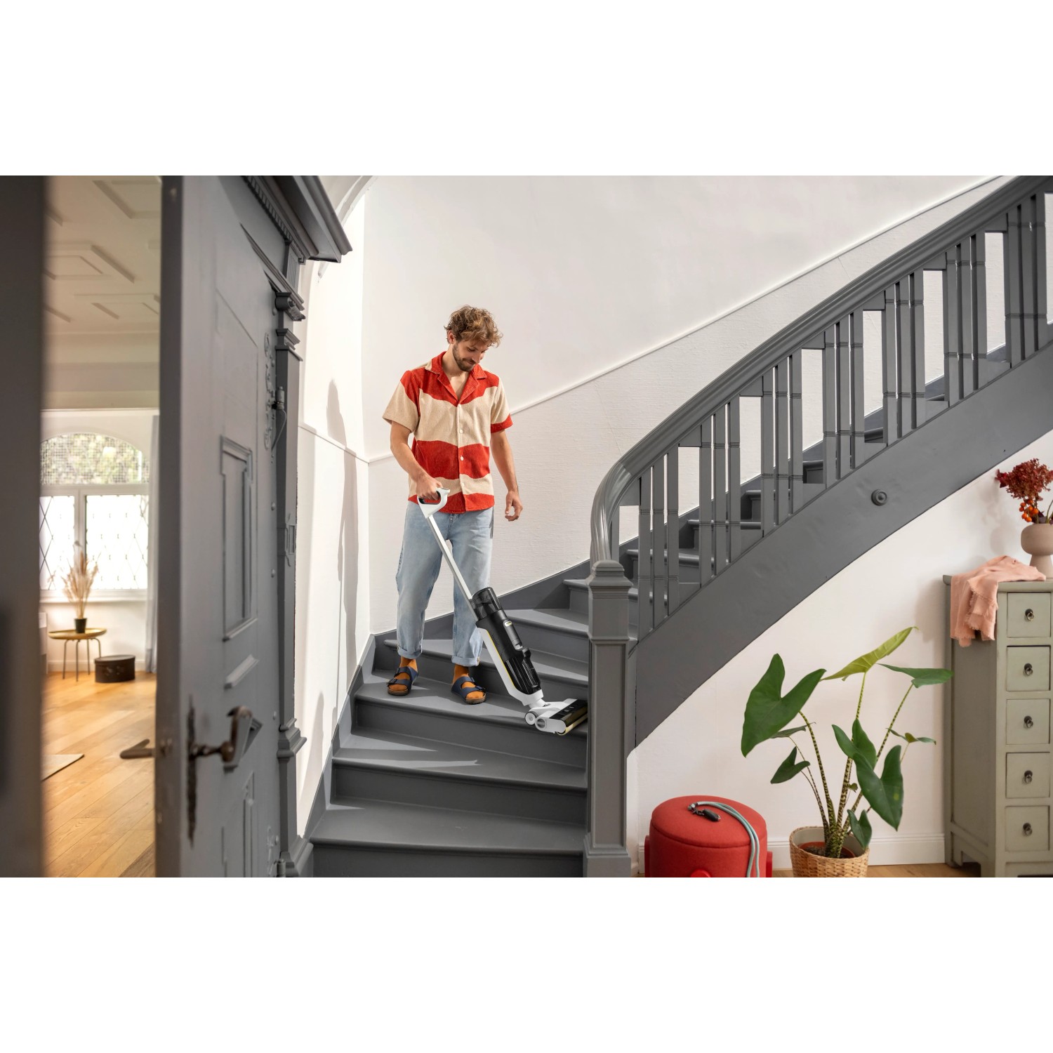 Mann reinigt Treppe mit Kärcher 3-in-1 Akku-Saugwischer FCV 3. Reinigungsgerät für Saugen, Wischen und Trocknen.