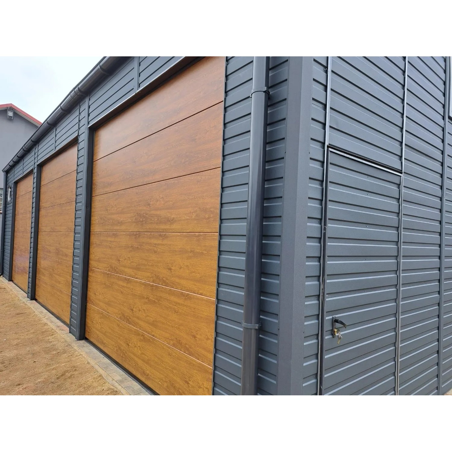 Große Liderstal Fertiggarage 12x8m in Graphit mit drei Sektionaltoren in Goldene Eiche Holzoptik und Seitentür.