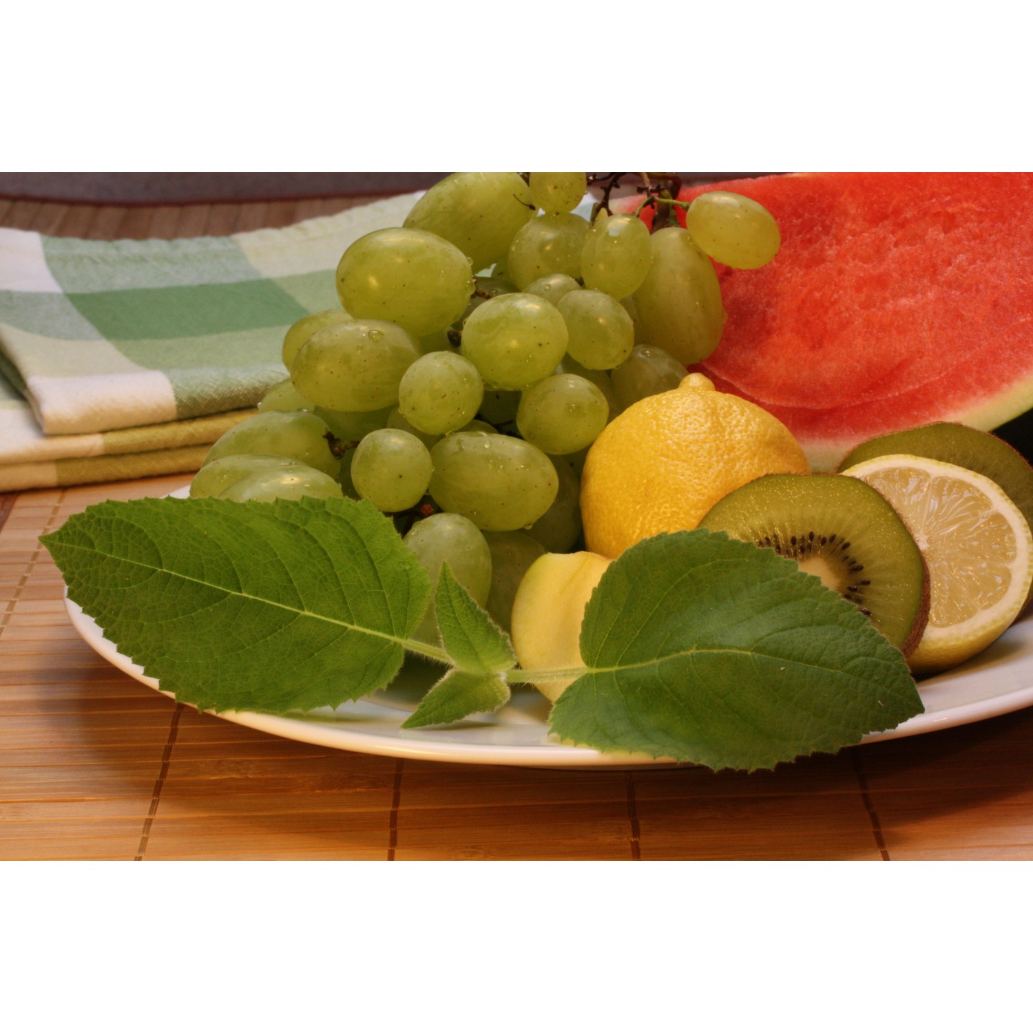 Frischer Fruchtsalat mit Salbei: Trauben, Zitrone, Kiwi und Wassermelone mit Salbei-Blättern.