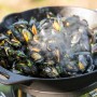 Petromax Feuerpfanne FP30-T: Gusseisenpfanne mit dampfenden Muscheln, ideal zum Grillen.
