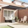 Anthrazitfarbene, einziehbare Markise an Backsteinhaus, spendet Schatten über Terrasse mit Gartenmöbeln. Polyester & Metall.