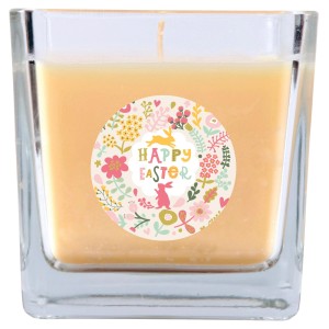 Cremefarbene Duftkerze im Glas mit Ostermotiv (Blumen, Hase) für eine gemütliche Atmosphäre.