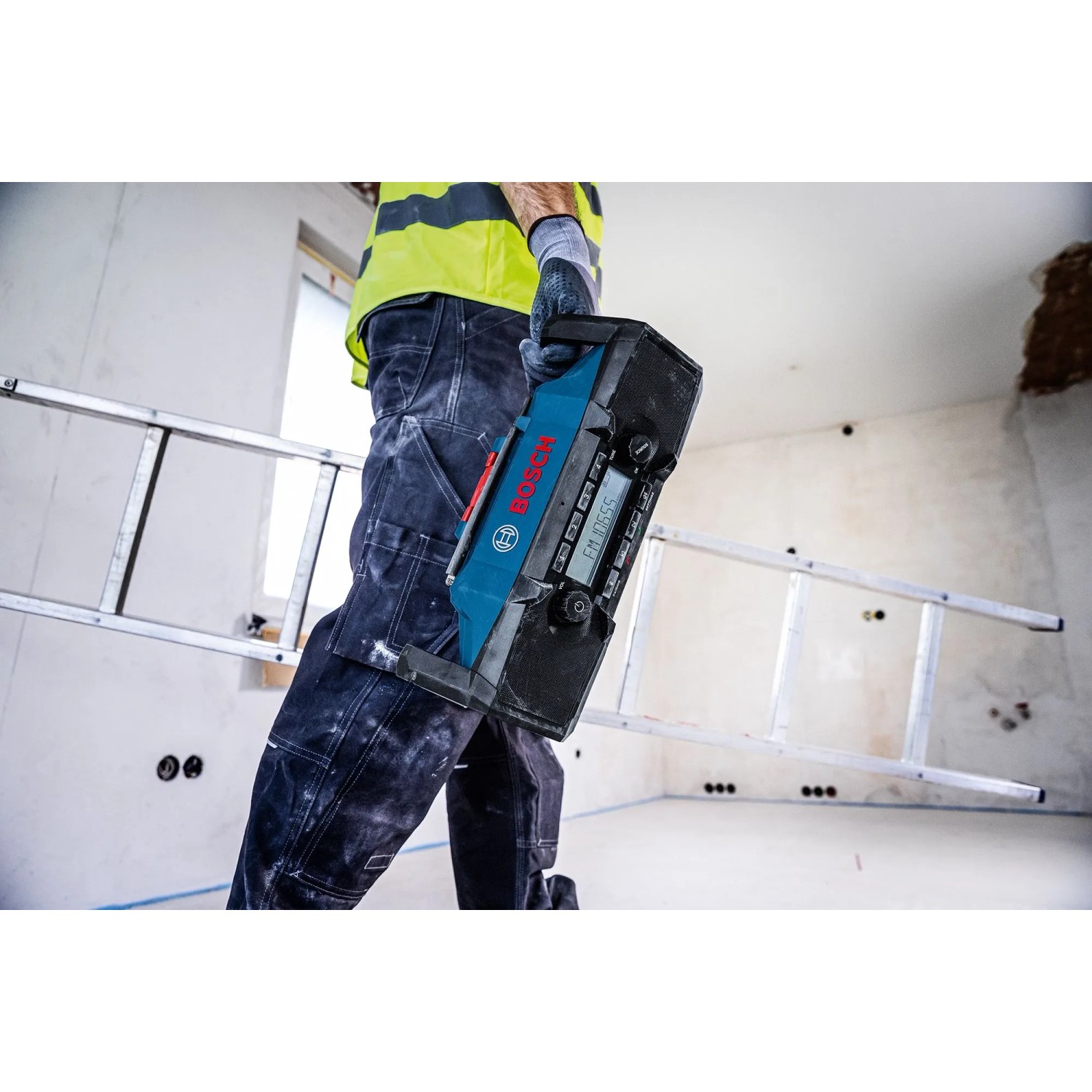 Bosch Professional GPB 18V-3SC Akku-Radio/Lautsprecher, getragen von einer Person auf einer Baustelle.