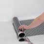 Verlegen der Heizfolie zur Fußbodentemperierung (130W/m²) auf einer reflektierenden Oberfläche.