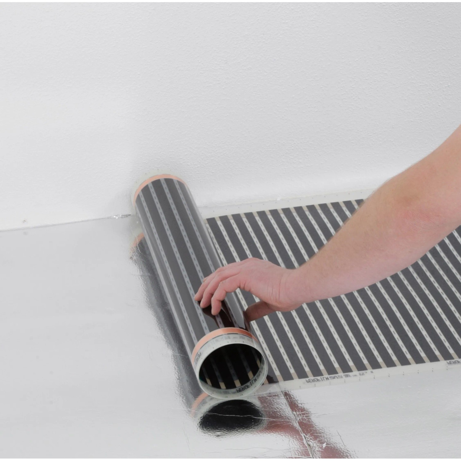 Verlegen der Heizfolie zur Fußbodentemperierung (130W/m²) auf einer reflektierenden Oberfläche.