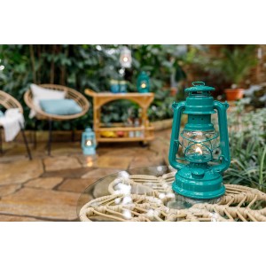 Türkisfarbene Feuerhand Sturmlaterne Baby Special 276 auf Tisch im Garten.