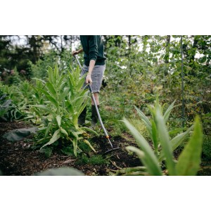 Person arbeitet mit Fiskars Ergonomic Hacke im Garten. Besen & Rechen für die Gartenarbeit.