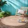 Beiger, runder Ayyildiz Outdoor-Teppich Comilla (120x120 cm) auf Terrasse mit Stuhl und Deko.