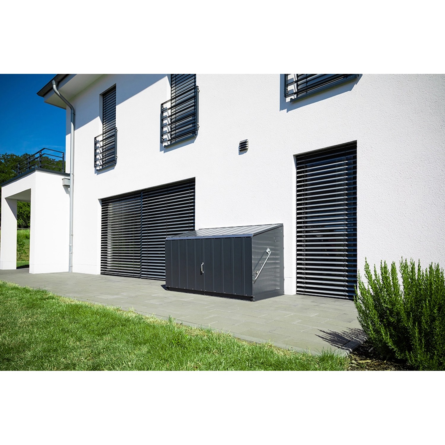 Anthrazitfarbene Trimetals Storeguard Aufbewahrungsbox (196x89 cm) vor weißer Hauswand.