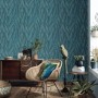 Erismann Vliestapete Martinique Retreat blau mit Blätterstruktur im Wohnraum.