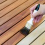 Auftragen von Bondex Wetterschutz-Öl Teak auf Holzterrasse mit Pinsel.