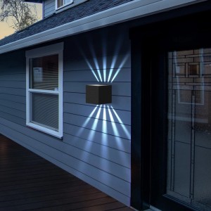 Schwarze, würfelförmige LED-Wandleuchte mit kaltweißem Up-Down-Licht an grauer Hauswand. IP65 für Innen & Außen.