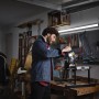 Mann arbeitet unter Osram LED-Lichtleiste Power Batten in Werkstatt. Weiße LED-Leuchte für Wand- und Deckenmontage.