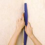 LUX Beschneidelineal 60 cm im Einsatz: Tapete wird mit Messer zugeschnitten.