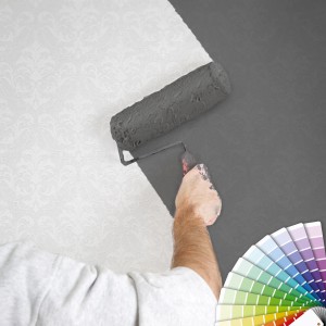 Überstreichen einer weißen Bricoflor Ornament Vliestapete mit grauer Farbe.