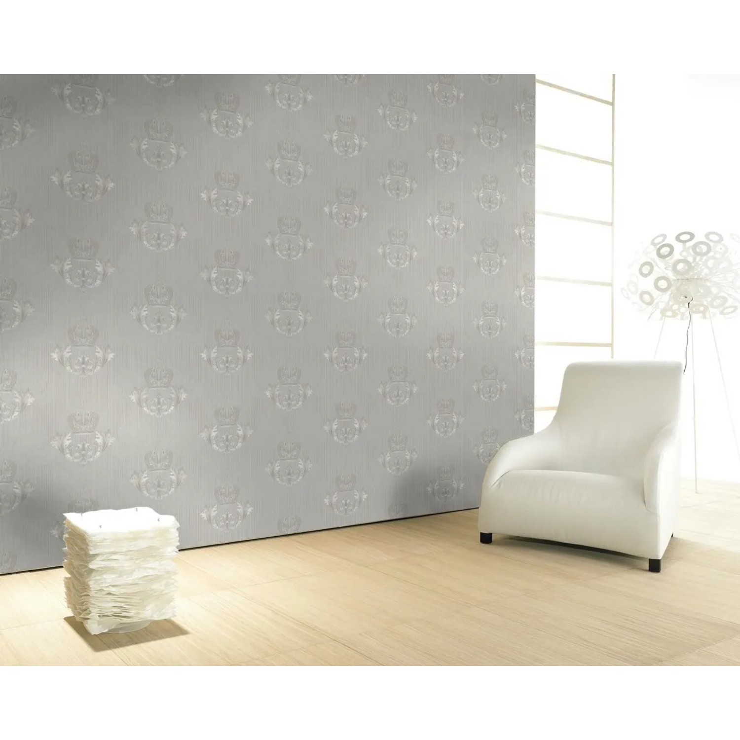 Glööckler Vliestapete Grau mit Krone und Blattmotiv in Wappenoptik an einer Wand.