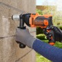 Black+Decker Schlagbohrmaschine BEH850K beim Bohren in eine Wand, mit Zusatzhandgriff.