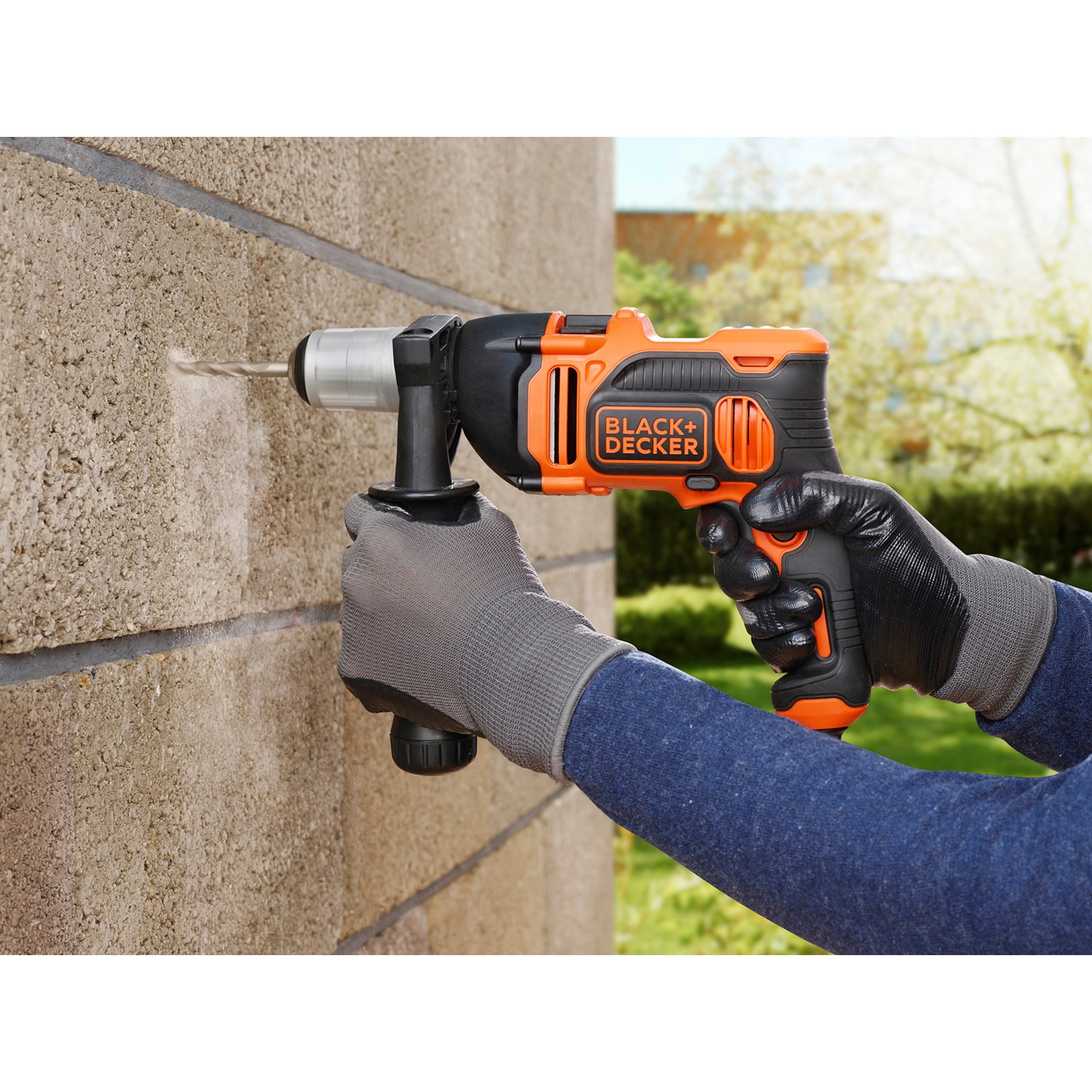 Black+Decker Schlagbohrmaschine BEH850K beim Bohren in eine Wand, mit Zusatzhandgriff.