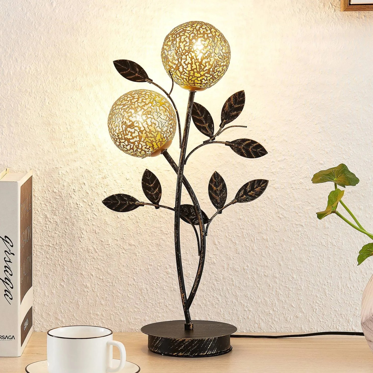 Schwarze Lucande Tischlampe Evory im Florentiner Design mit zwei floralen Lampenschirmen.