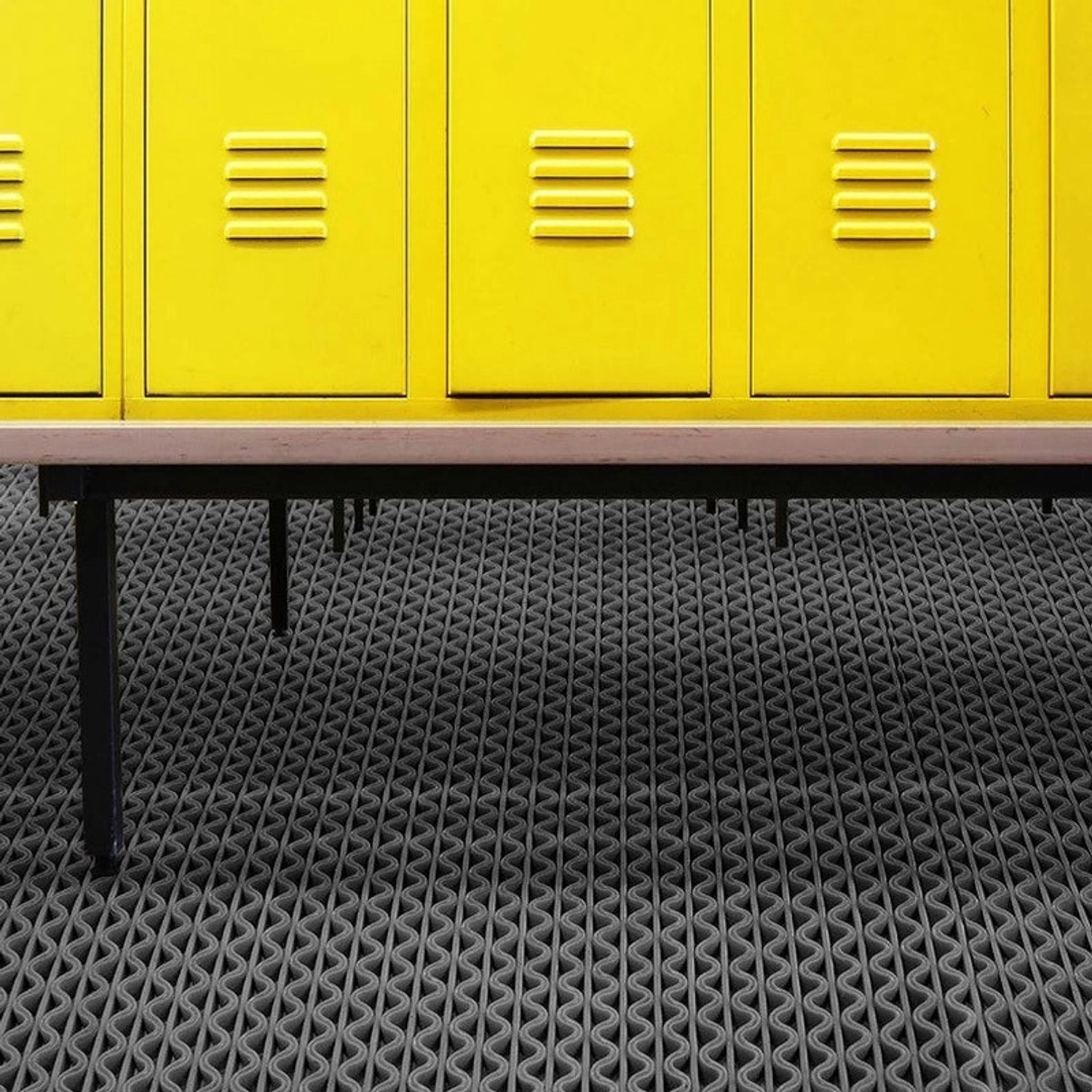 Graue KARAT Hygienematte 90x50 cm für Barfußzonen vor gelben Spinden.