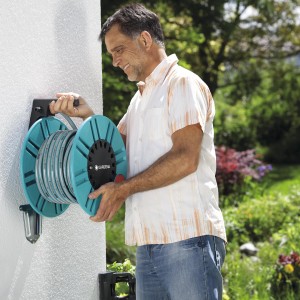 Gardena Classic Wand-Schlauchtrommel 60 mit Mann beim Aufrollen des Gartenschlauchs.