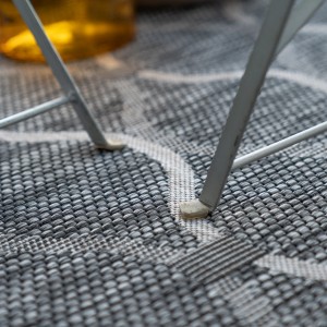 Detailaufnahme: Grauer Obsession Teppich Nordic 871 (Indoor/Outdoor) unter einem Stuhlbein.