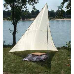 Sandfarbenes Floracord Dreieckssonnensegel, aufgestellt am Wasser mit Decke und Kissen.