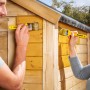 Holzschutzlasur Farblos von Xyladecor beim Auftragen auf ein Gartenhaus.