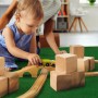 Kind spielt auf dunkelgrünem Primaflor Rasenteppich Garden B1 mit Holzspielzeug.