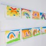 Weiße Artiteq Info Rail Aufhängeschiene (1 m) mit Kinderzeichnungen an einer Wand.