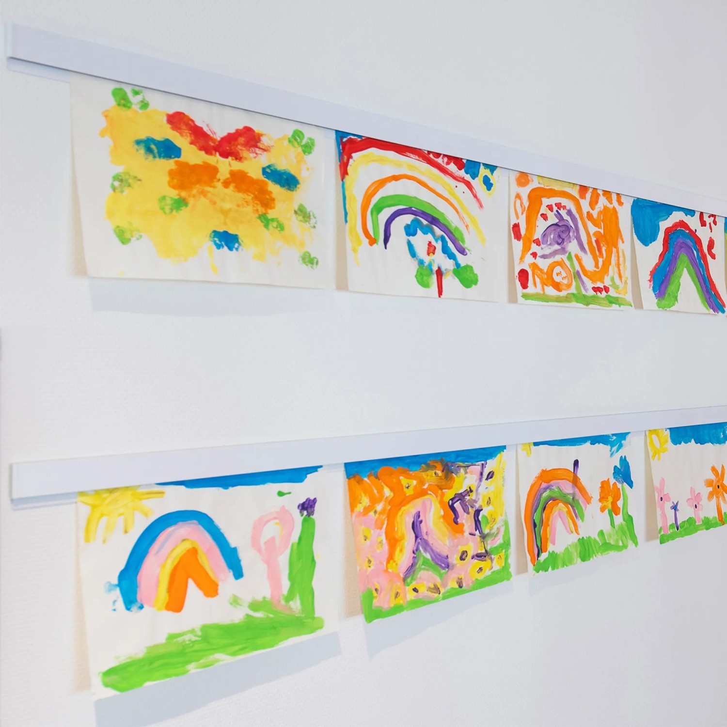 Weiße Artiteq Info Rail Aufhängeschiene (1 m) mit Kinderzeichnungen an einer Wand.