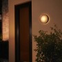 Schwarze Philips Hue Daylo Wandleuchte mit warmweißem Licht im Außenbereich.