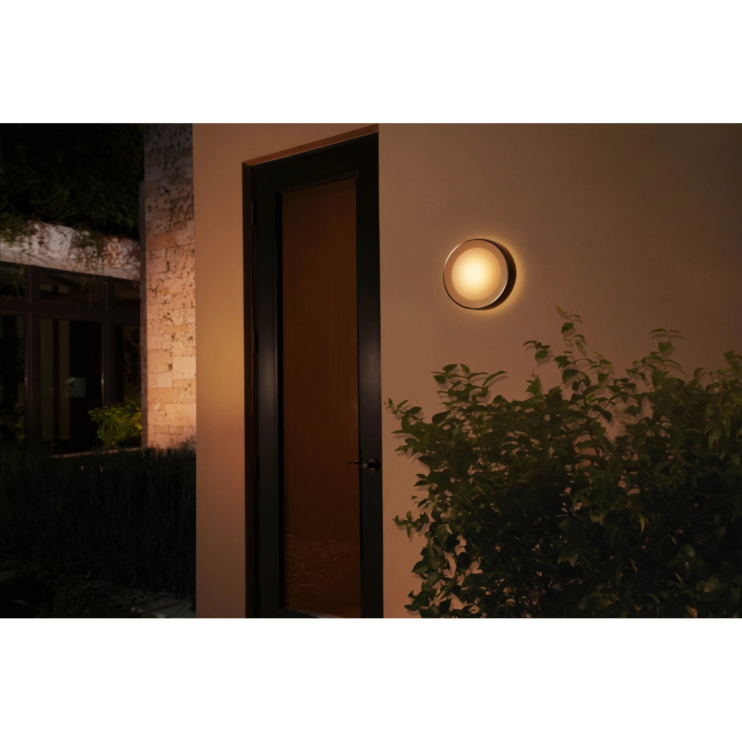 Schwarze Philips Hue Daylo Wandleuchte mit warmweißem Licht im Außenbereich.