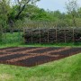Dunkelbraune, flexible Beeteinfassung aus Tannenholz um ein Gartenbeet auf Rasen. Ideal für klare Abgrenzungen im Garten.