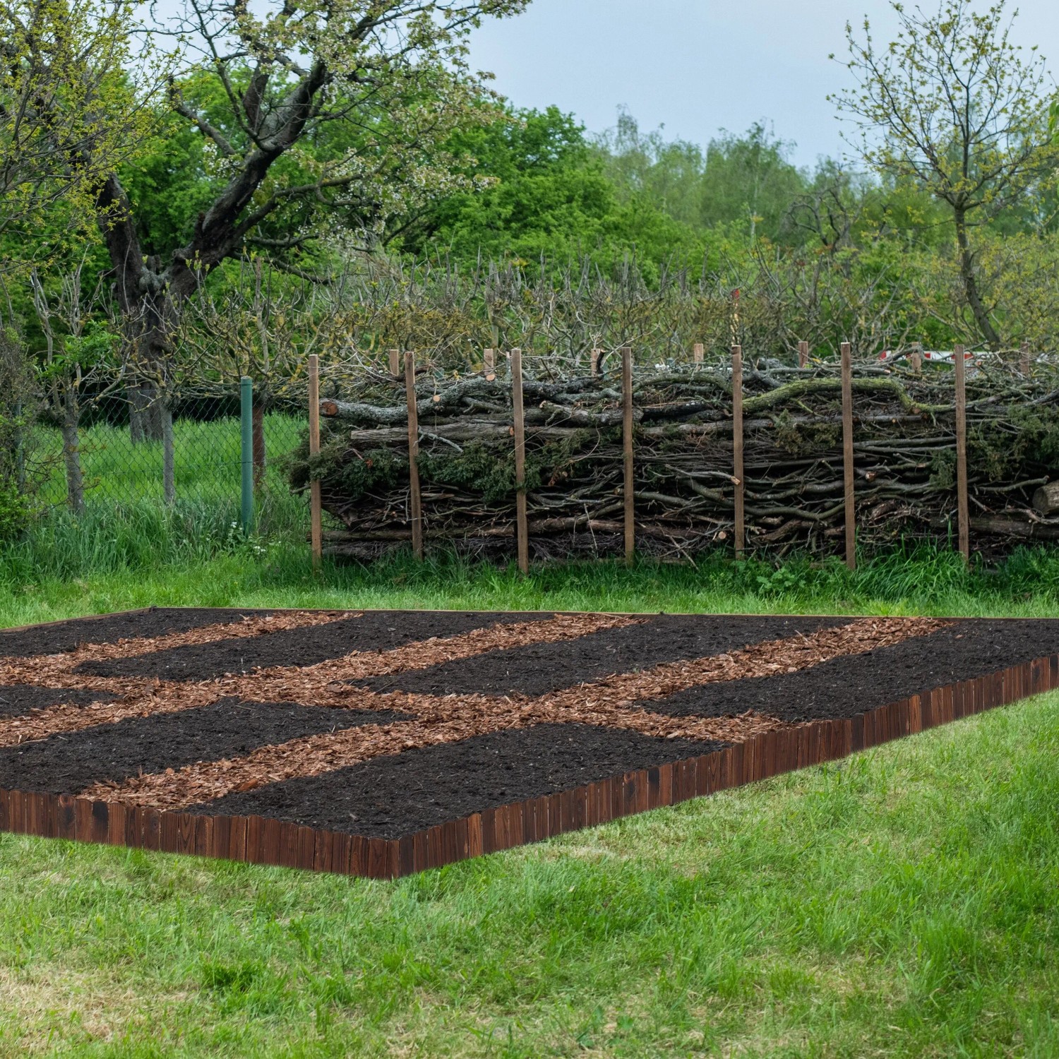 Dunkelbraune, flexible Beeteinfassung aus Tannenholz um ein Gartenbeet auf Rasen. Ideal für klare Abgrenzungen im Garten.