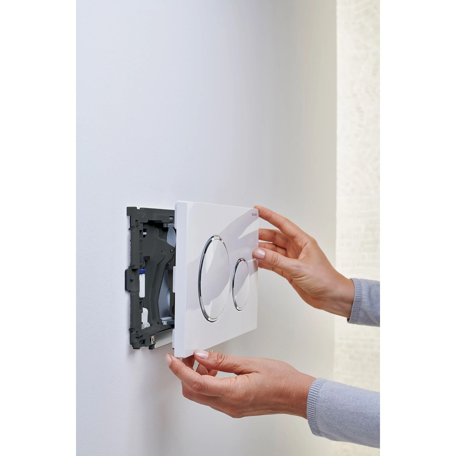 Weiße Geberit WC-Drückerplatte mit Chromtasten wird in Wand montiert. Für Sigma UP-Spülkasten, DuoFresh Stick.
