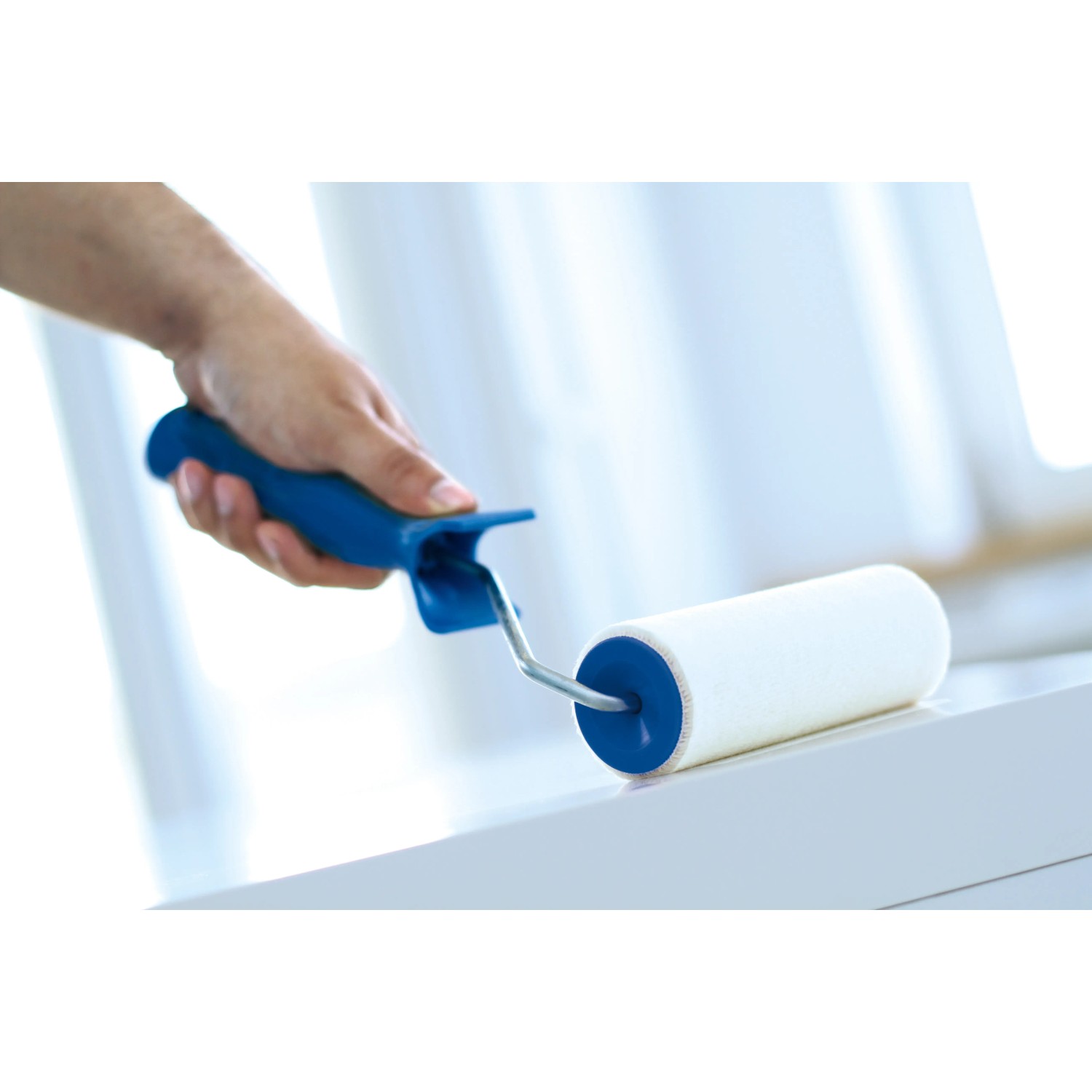 Hand hält LUX Velours-Roller (15 cm) beim Streichen auf weißer Oberfläche.