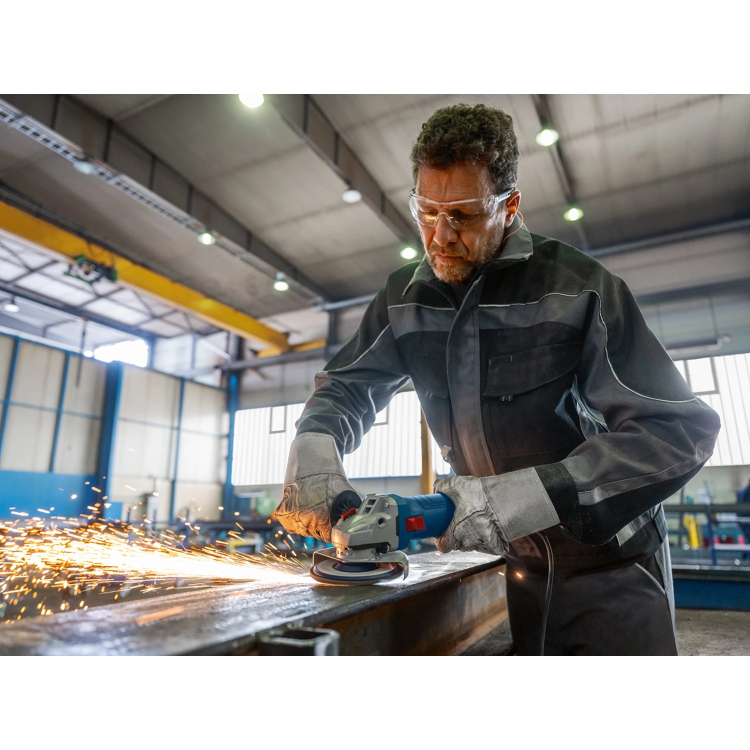 Mann schleift Metall mit dem Bosch Professional Winkelschleifer GWS 12-125, Funken sprühen.