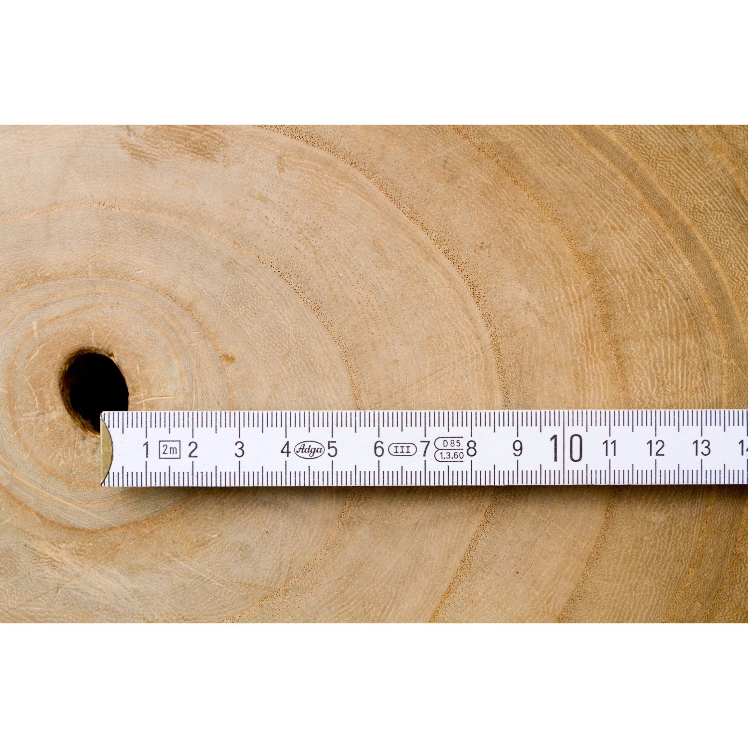 Holzscheibe mit Loch und Zollstock zur Messung, Fokus auf Details des Blu CO2-Klimabaums.