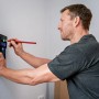 Mann benutzt Bosch Professional GMS 120-27 Ortungsgerät an Wand zur Lokalisierung.