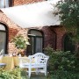 Weißes Floracord Sonnensegel 330x200 cm über Terrasse mit Gartenmöbeln.