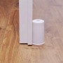 Weißer Wagner Boden-/Wandtürstopper Vulkano aus Gummi (Ø 45 mm x 75 mm) neben Tür auf Holzboden.