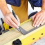Handwerker zeichnet Linie mit Dry Profi Baumarker und Winkel auf Holz.