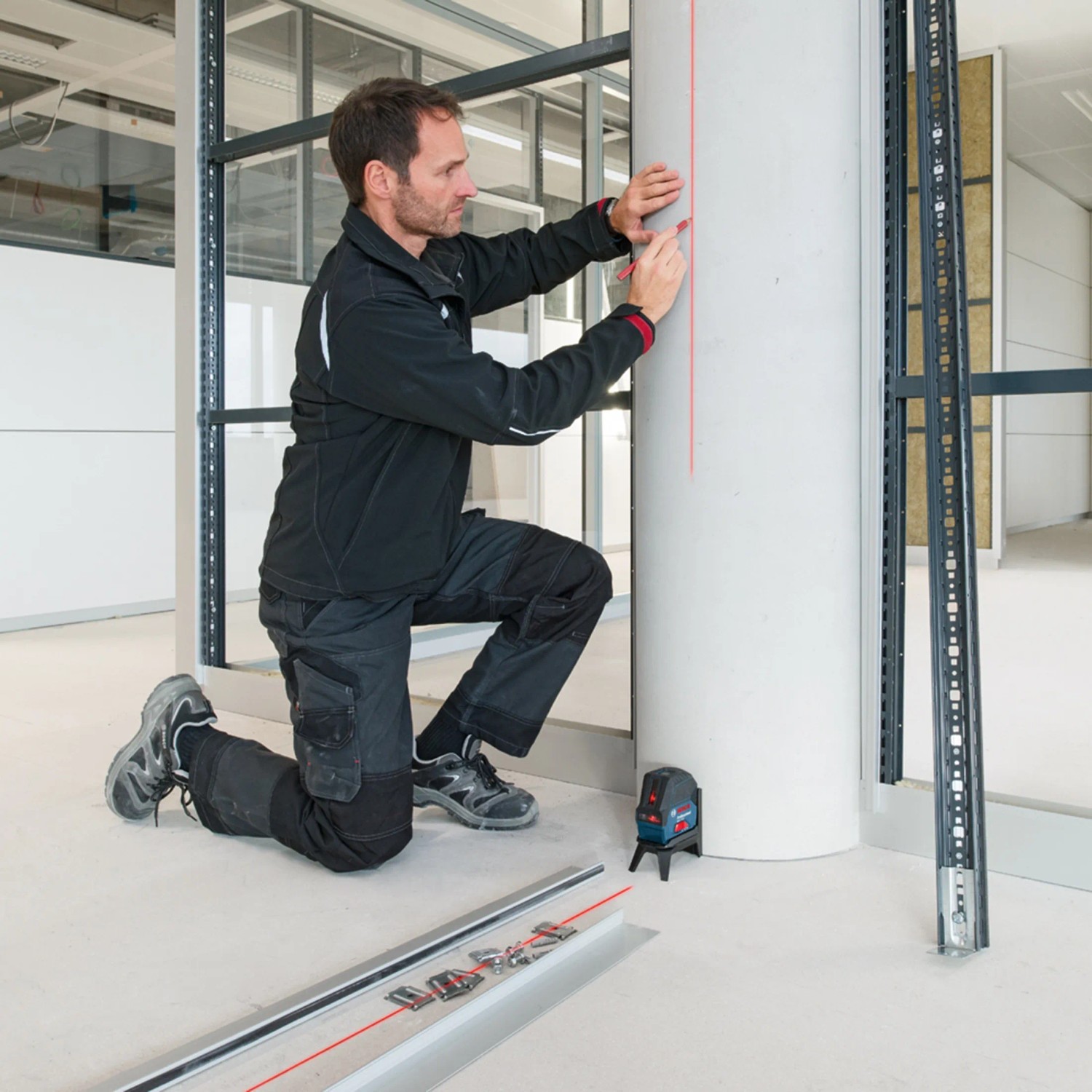 Mann markiert Linie mit Bosch Professional Linienlaser GCL 2-15 an Säule. Prüfwerkzeug für präzises Nivellieren.