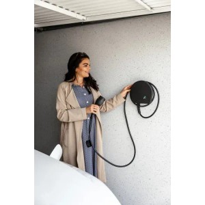 Frau bedient Alphatec Wallbox Mini (11kW) mit Kabel und Schukostecker an Wand. Plug and Play.