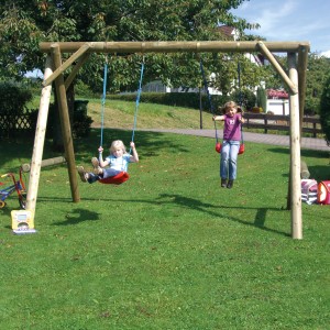 T&J Doppelschaukel Maxi aus Holz mit zwei Kindern im Garten.